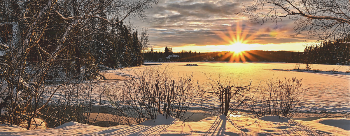 Wintersonnenaufgang über zugefrorenem See als Symbol für den Jahreswechsel in den Rauhnächten